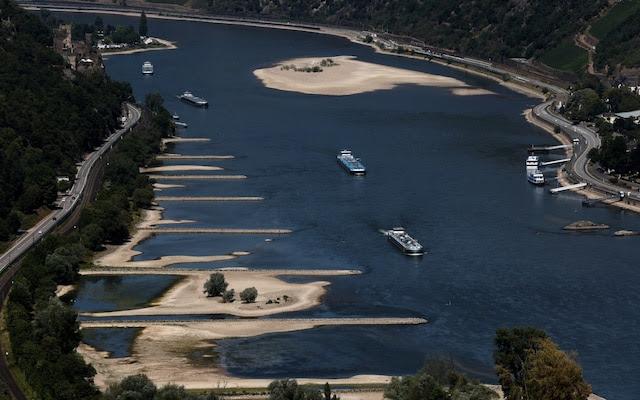 Transport vessels cruise past the partially dried riverbed of the Rhine river in Bingen, Germany CREDIT: WOLFGANG RATTAY/REUTERS