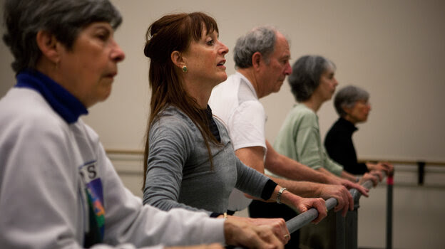 Dance teacher Lucy Bowen McCauley (second from left) finds that simply humming can help her students with Parkinson's get their feet to "unfreeze" and match the song's rhythm. Dance teacher Lucy Bowen McCauley (second from left) finds that simply humming can help her students with Parkinson's get their feet to "unfreeze" and match the song's rhythm.
