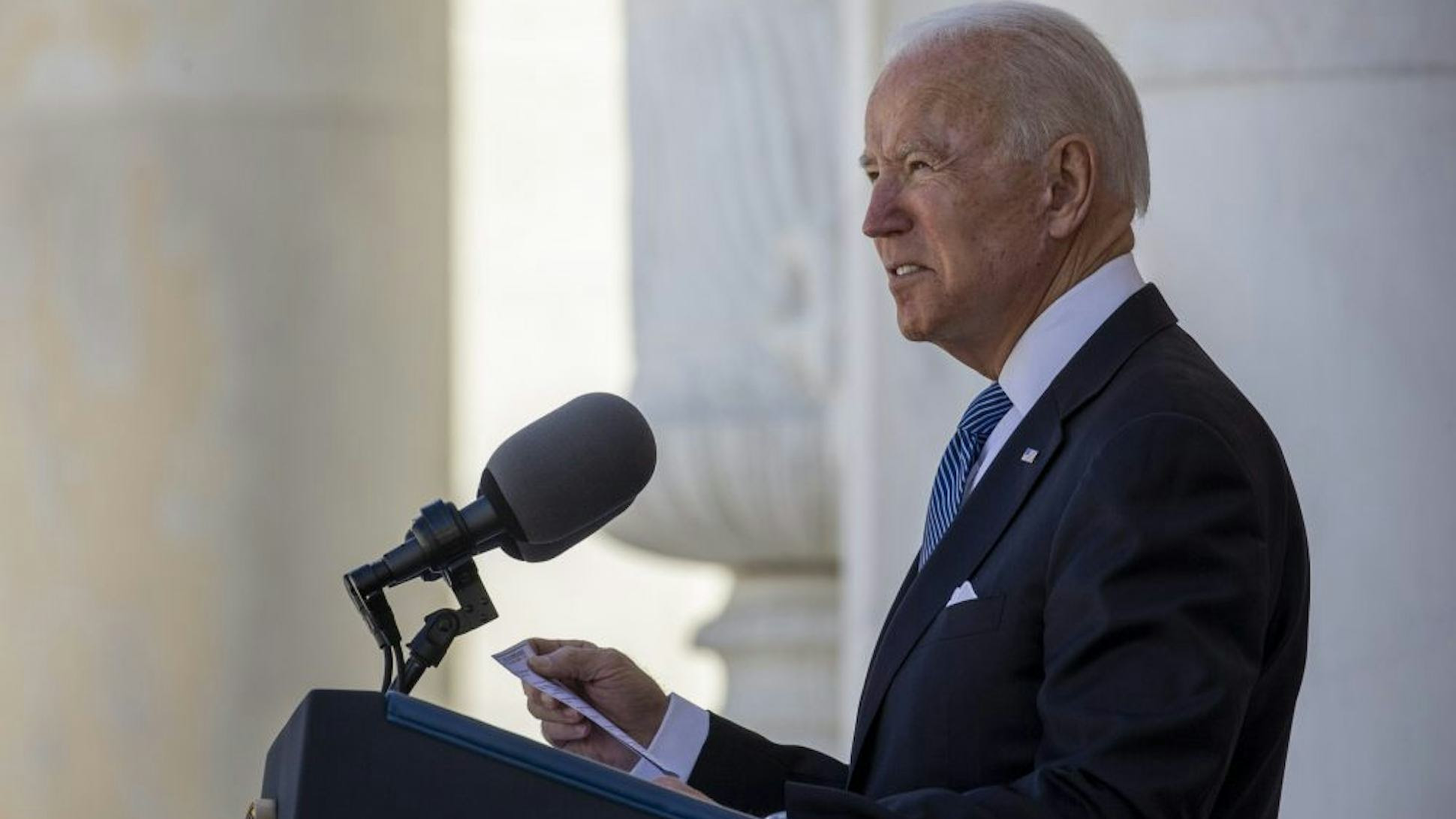 President Joe Biden stands behind a podium, giving a speech