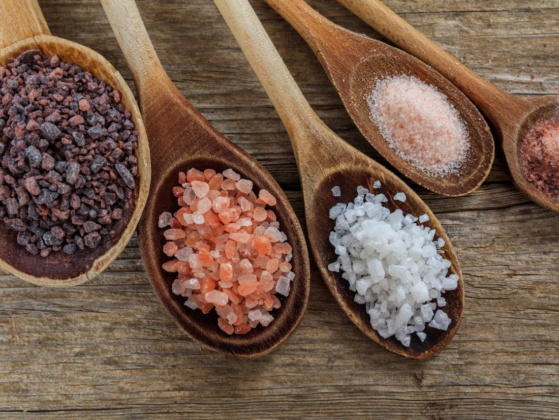 a variety table salts and sea salts on wooden spoons