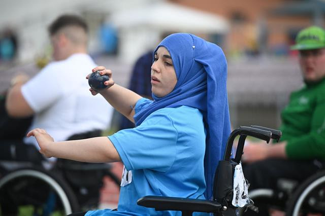 A young woman in her wheelchair throwing a shot put