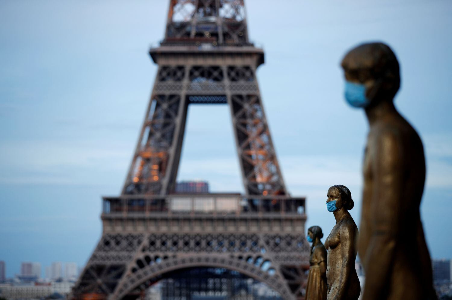 Estatuas con mascarillas en el Trocadero de París, con la Torre Eiffel al fondo.