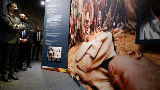 Le président français Emmanuel Macron (G) et le ministre français des Affaires européennes et étrangères Jean-Yves Le Drian s'arrêtent pour regarder des images lors de leur visite au Mémorial du génocide de Kigali, où sont enterrées quelque 250 000 victimes des massacres, à Kigali, le 27 mai 2021.