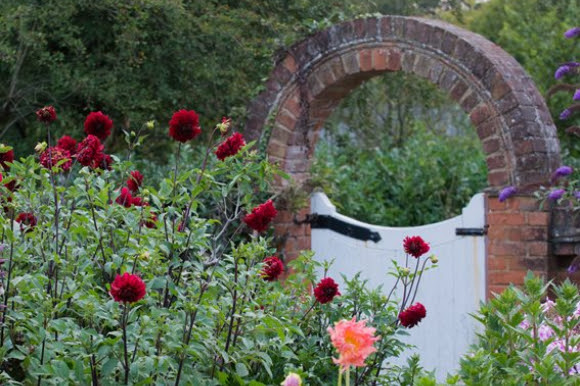 View of an English garden with a brick archway and flowers