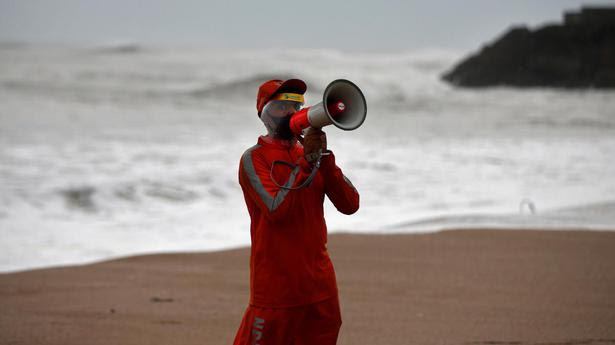 A member of the National Disaster Response Force (NDRF) uses a megaphone to appeal to fishermen to stay away from the shore ahead of Cyclone Tauktae in Veraval, Gujarat, India, May 17, 2021.