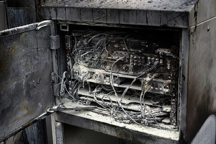Damaged cabling and telecommunications equipment is pictured following a fire at a phone mast, attatched to the chimney at the converted Fearnleys Mill residential apartment block complex in Huddersfield, northern England, on April 17, 2020. - It is not yet known what caused the mast, which is attached to a chimney at the Fearnleys Mill development, to go up in flames. But the fire comes after a number of mobile phone masts have been set on fire amid claims of a link between 5G and the novel coronavirus COVID-19. 