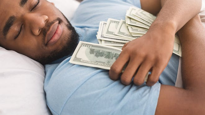 Man clutches money while he sleeps