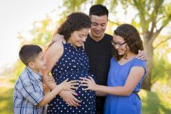 image of a family gathered around pregnant mom, with hands on her belly