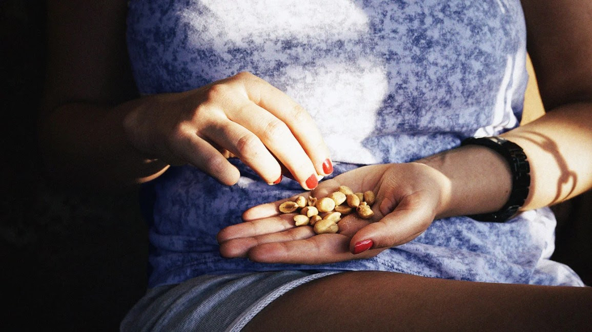 person eats nuts from hand to lower uric acid levels