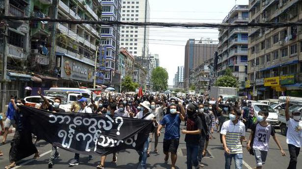 Call for support: Anti-coup protesters marching on a street in Yangon on Friday.