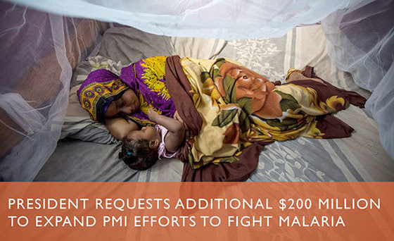 A mother and her child lay on a bed under treated mosquito nets.