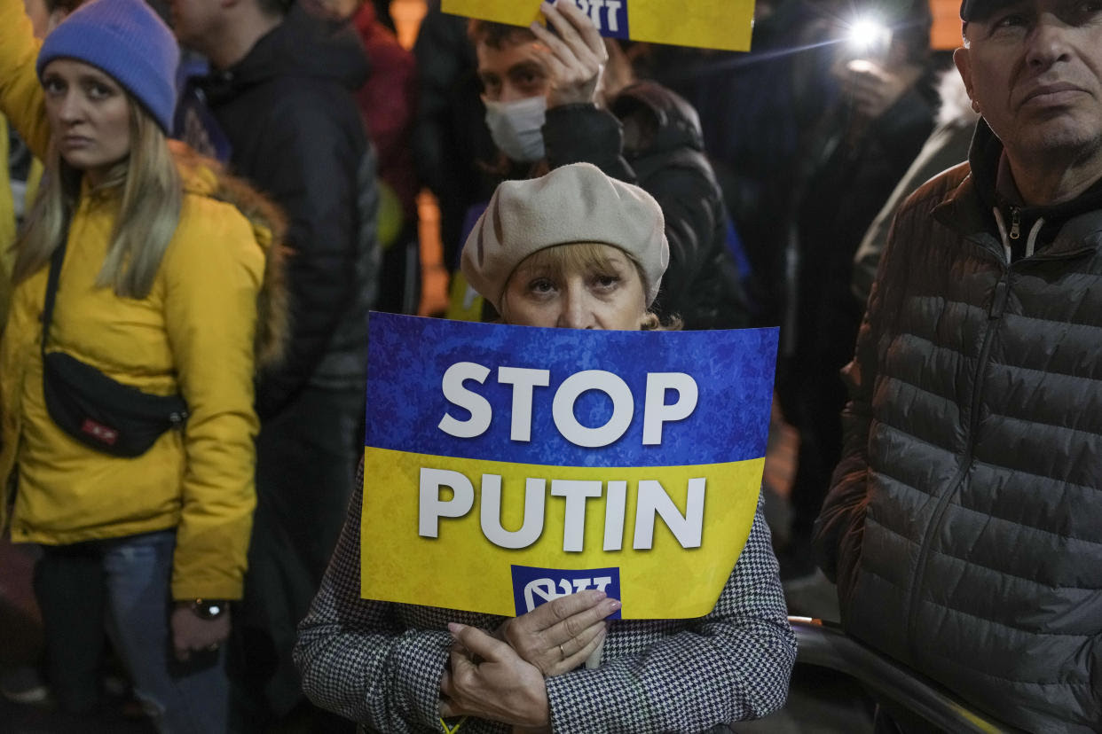 People in Tel Aviv hold blue-and-yellow Stop Putin signs at a protest.