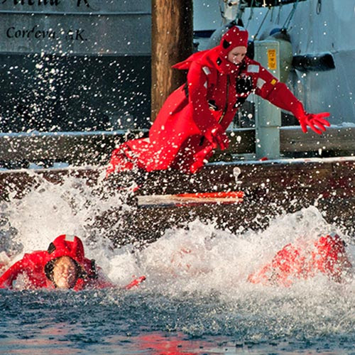 people in survival suits jumping into the water
