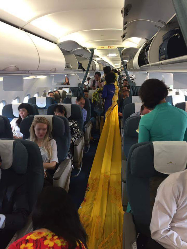 Vợ MC Thanh Bạch diện áo dài như đuôi công lên máy bay khiến nhiều hành khách choáng - Ảnh 4.