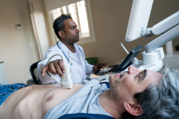 Doctor haciendo una ecografía del corazón a un paciente masculino de mediana edad