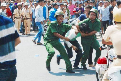 Các nhân viên mặc sắc phục kẹp cổ một biểu tình viên. Nguồn: internet