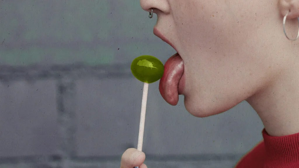 A person licking, and tasting, a lollipop.