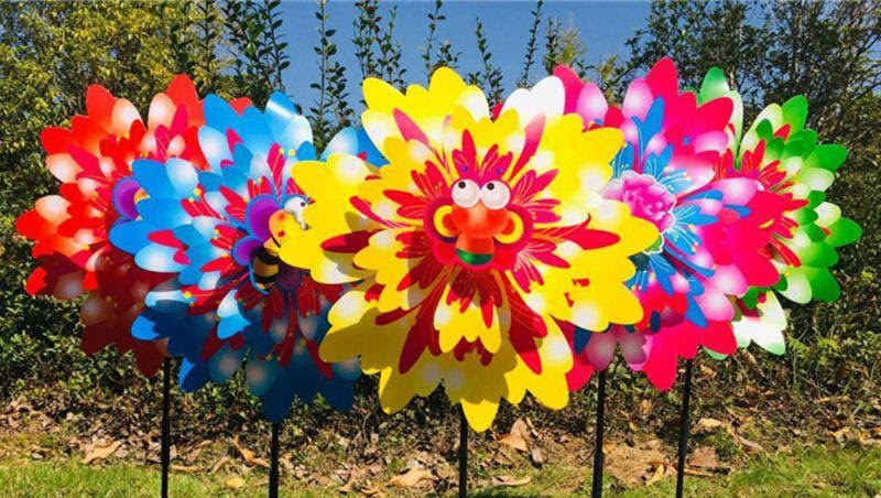 Colorful pinwheels in front of grass and trees.
