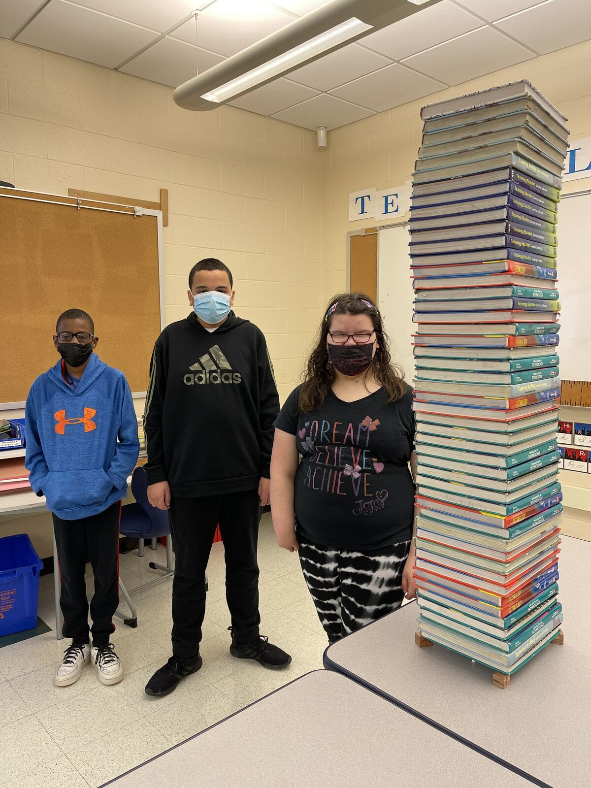 students posing next to stacked books