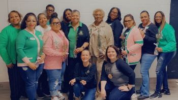 A second group of Alpha Kappa Alpha Sorority, Inc. members holding seedlings and DNR trainers pose for a photo