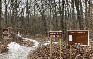 new signs showing open hours and Recreation Passport requirement at trail entrance in woods at Van Buren State Park