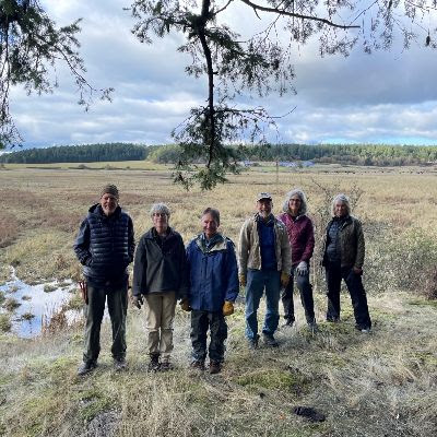 Six people standing in a wintery field of brush