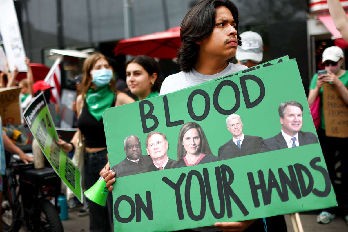 一名堕胎权利活动家在计划生育诊所外的示威活动中举着一个标语，上面描绘了最高法院大法官克拉伦斯·托马斯、塞缪尔·A·阿利托、小艾米·科尼·巴雷特、尼尔·M·戈萨奇和布雷特·M·卡瓦诺，因为他们保护诊所免受极右翼团体可能于 2022 年 7 月 16 日在加利福尼亚州圣莫尼卡举行抗议。