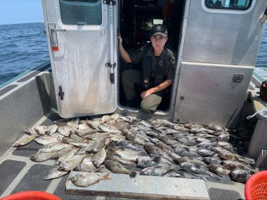 ECO kneels in boat next to 100 fish illegal caught