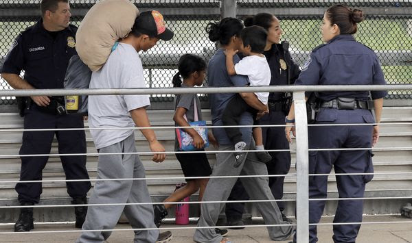 In this Thursday, June 21, 2018, file photo, Ever Castillo (left) and his family, immigrants from Honduras, are escorted back across the border by U.S. Customs and Border Patrol agents in Hildalgo, Texas. The U.S. Justice Department is in talks to pay hundreds of thousands of dollars to each child and parent who was separated under a Trump-era practice of splitting families at the border. (AP Photo/David J. Phillip) ** FILE **