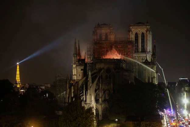 Slide 5 of 31: Firefighters douse flames billowing from the roof at Notre-Dame Cathedral in Paris on April 15, 2019. - A colossal fire swept through the famed Notre-Dame Cathedral in central Paris causing the spire to collapse and raising fears over the future of the nearly millenium old building and its precious artworks. The fire, which began in the early evening, sent flames and huge clouds of grey smoke billowing into the Paris sky as stunned Parisians and tourists watched on in sheer horror. (Photo by ludovic MARIN / AFP) (Photo credit should read LUDOVIC MARIN/AFP/Getty Images)