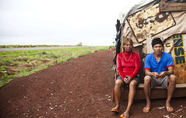 A Guarani-Kaiowa couple sit outside their makeshift roadside settlement of the Apy Ka&apos;y community, near Dourados, Mato Grosso do Sul, Brazil.