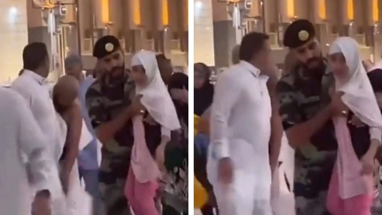 شاهد لافتة إنسانية لرجل أمن مع طفلة أثناء الرياح القوية في مكة