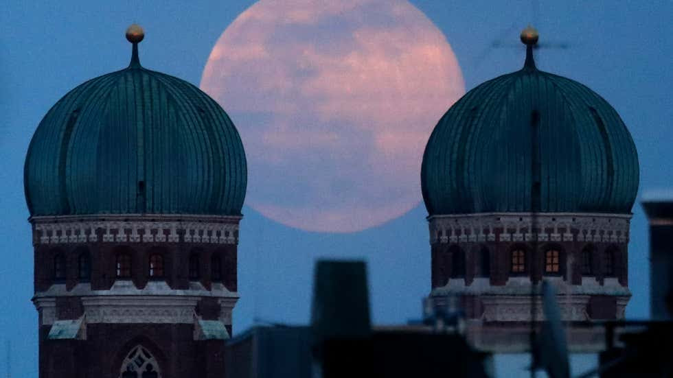 The full moon rises behind the Church of our Lady in Munich, Germany, Sunday, March 28, 2021