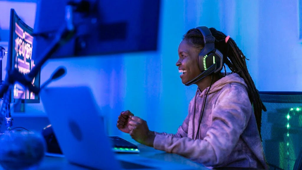 Black person wearing braids in a ponytail smiling while looking at a computer screen