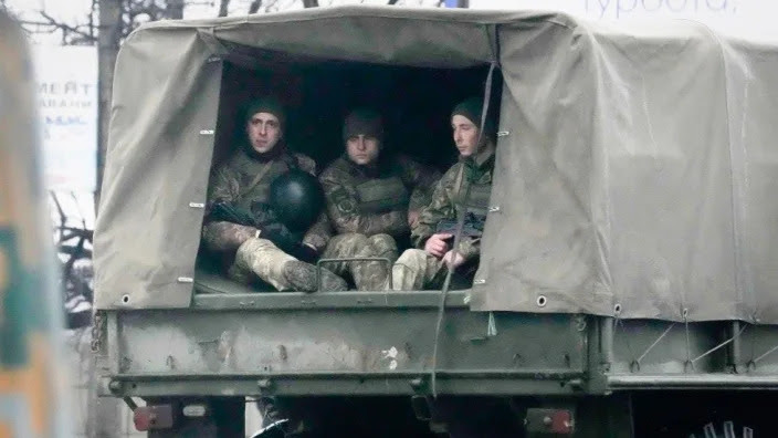 Ukrainian soldiers ride in a military vehicle in Mariupol