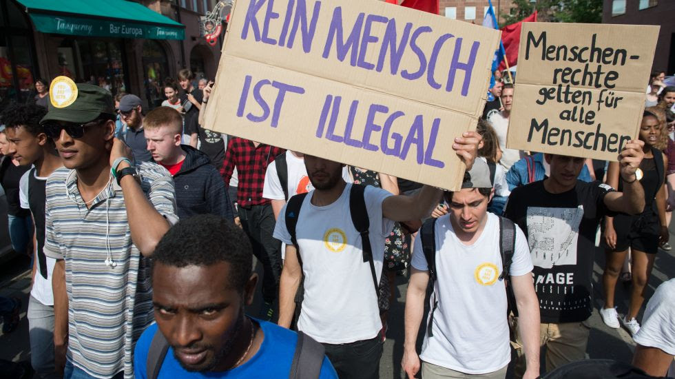 Teilnehmer einer Demonstration protestieren am 02.06.2017 in NÃ¼rnberg (Bayern) mit Schildern mit den Aufschriften "Menschenrechte gelten fÃ¼r alle Menschen" und "Kein Mensch ist illegal" gegen die bayerische Abschiebepraxis von FlÃ¼chtlingen.