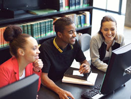 Diverse group of students working together on computer in library