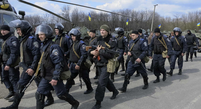 Los miembros del Ministerio del Interior de Ucrania pasan junto a un helicóptero militar MI-8 y vehículos blindados de transporte de personal en un puesto de control cerca de la ciudad de Izium, el este de Ucrania.