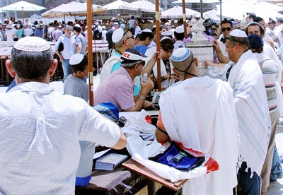 Jewish men pay respect to the
                Torah scroll at the Western (Wailing) Wall.