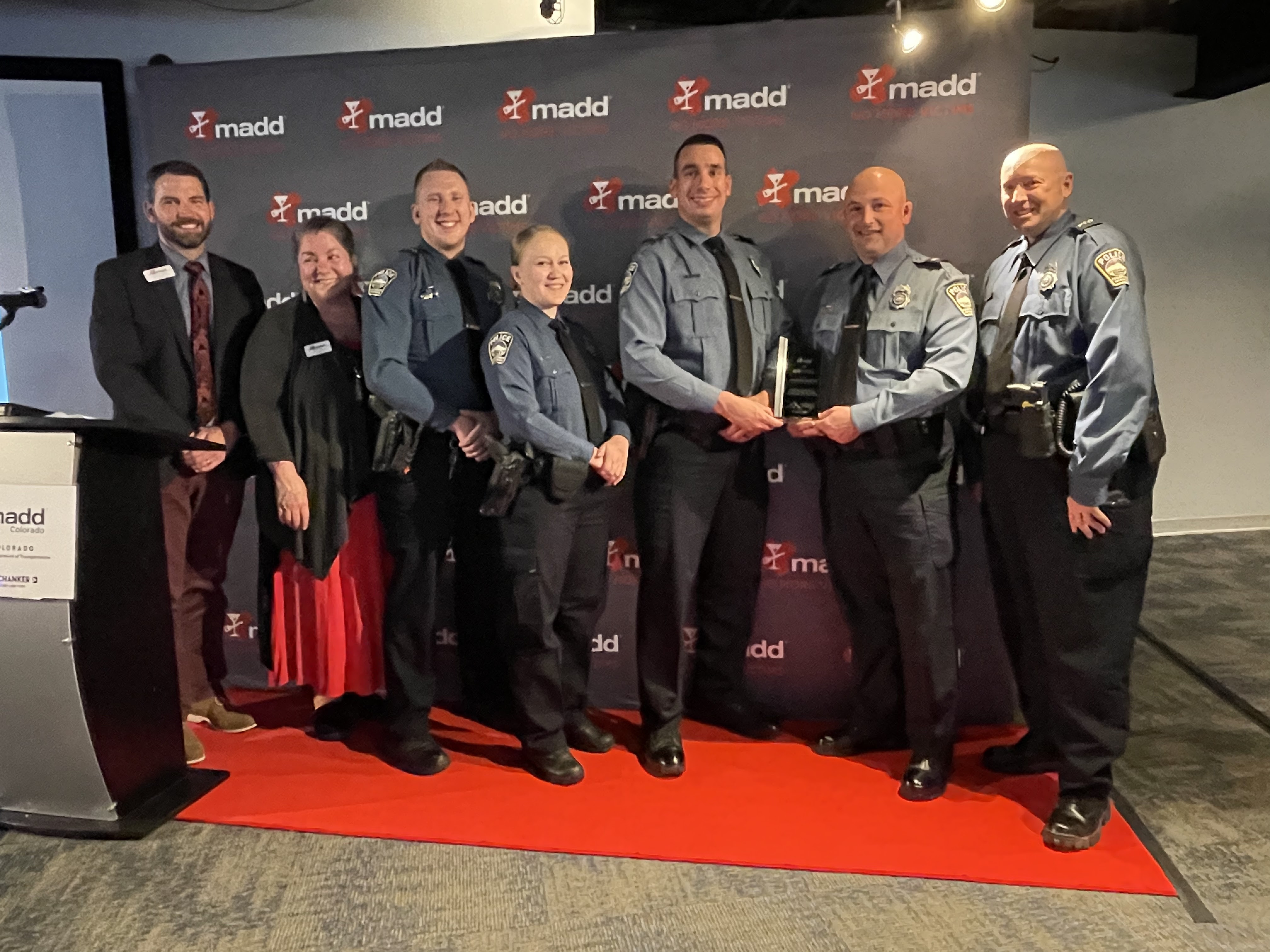 Colorado State Patrol DUI Unit (7 people) receive their award in front of red MADD podium 