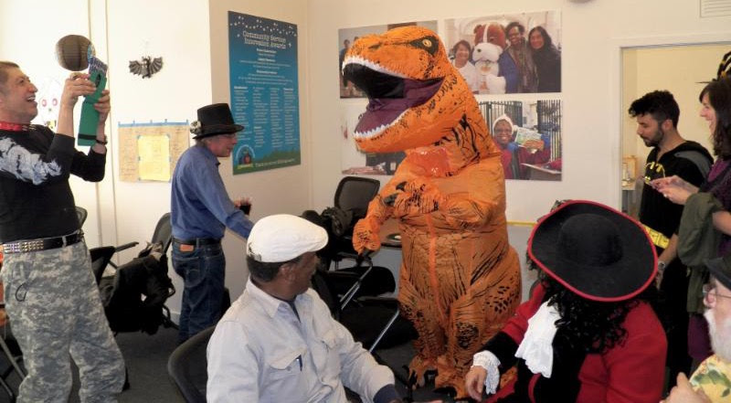 dinosaur in office with staff in costumes