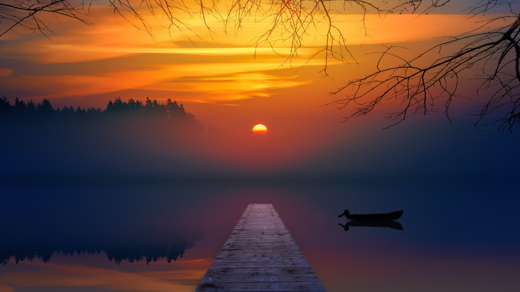 orange sunset in the mist over a lake with a dock and small rowboat