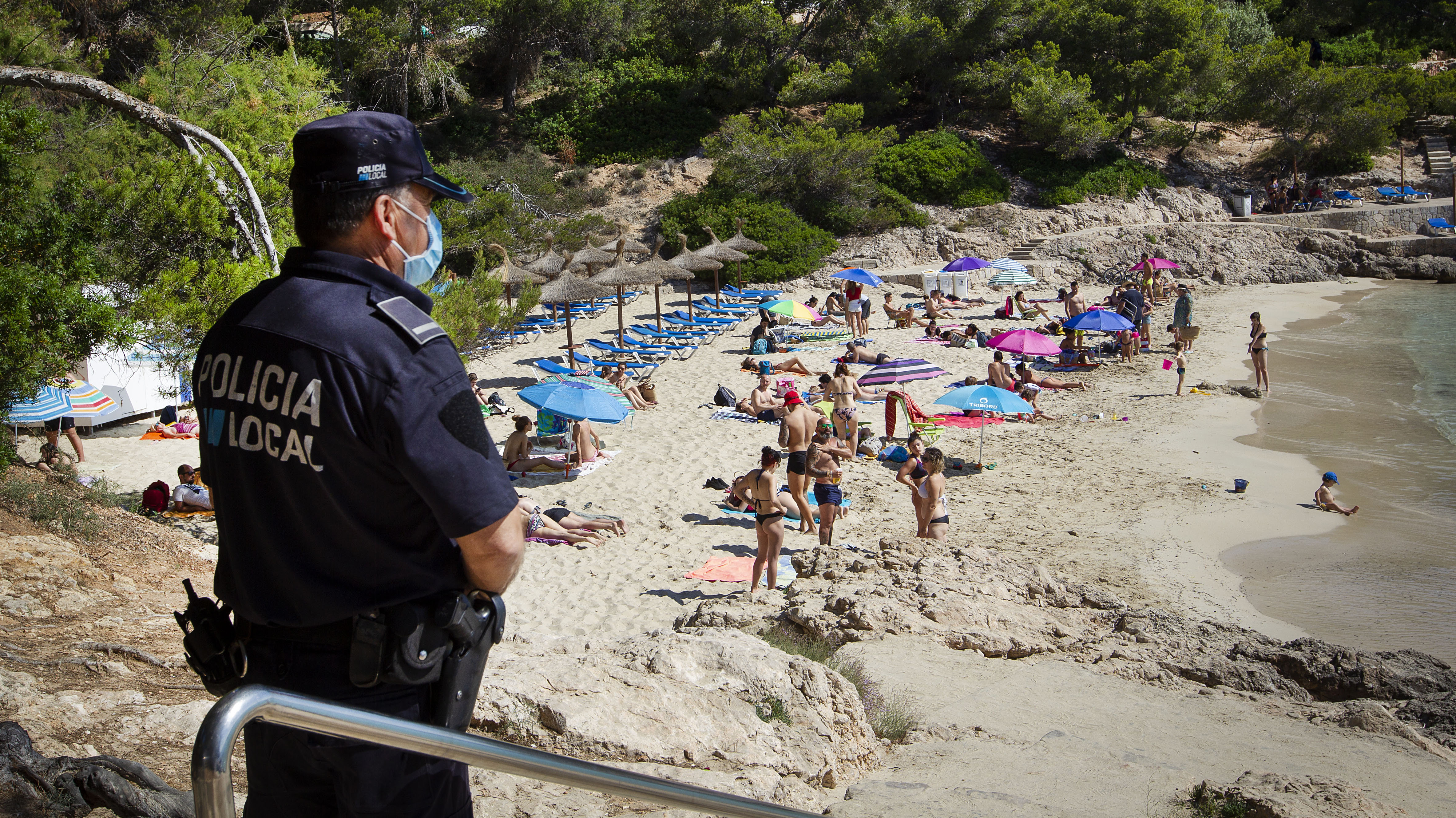 La policía local observa a las personas tomando sol en la playa de Cala Comtesa en Calvia, en la isla de Mallorca (AFP)
