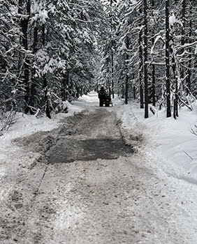 A rider stops a snowmobile after a water hole across a snowmobile trail.