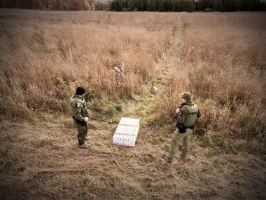 ECO and Ranger stand next to white box after releasing pheasants into a field