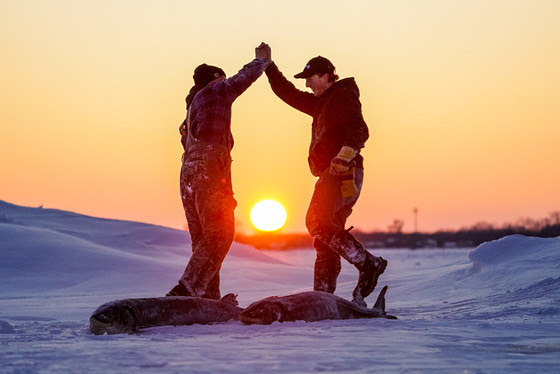 An image of two people celebrating after harvesting a sturgeon. 