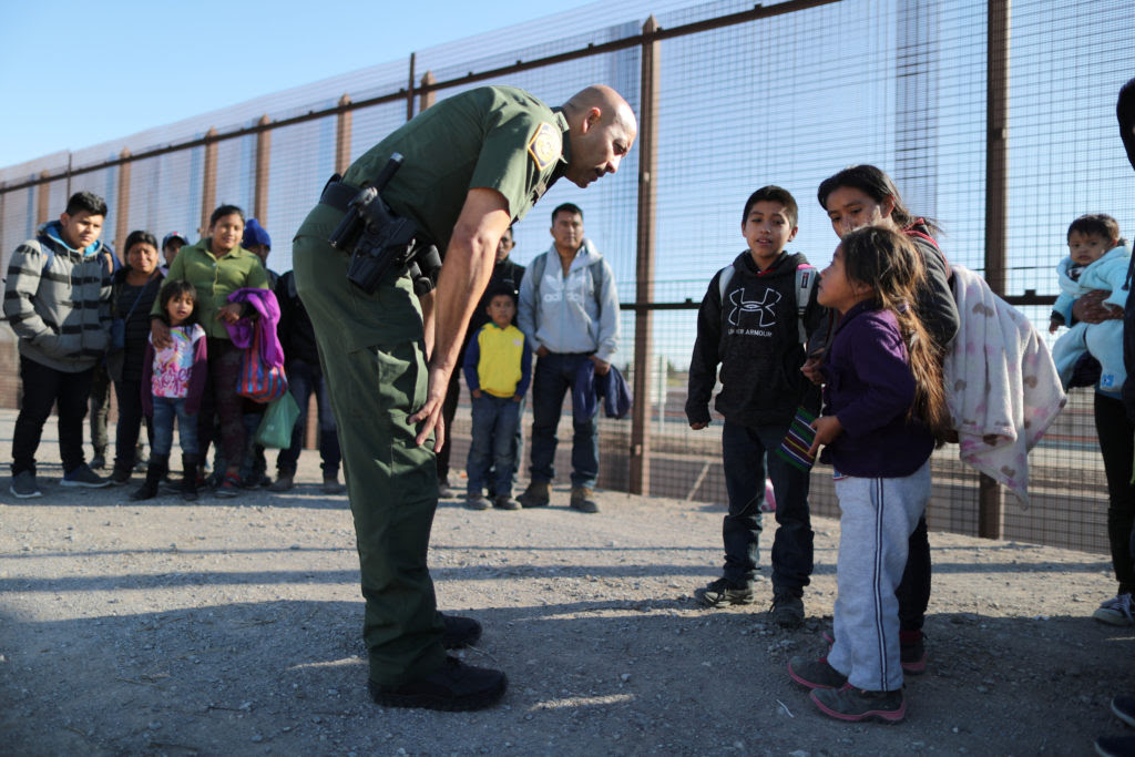Border patrol agent talking with immigrant families Border patrol agent talking with immigrant families