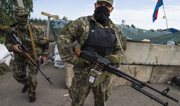 Masked pro-Russian armed militants guard a checkpoint with a Russian national flag on the right, blocking the major highway which links Kharkiv, outside Slovyansk, Ukraine, on May 24, 2014. Russia&#39;s present demands are based on Putin&#39;s purported long sense of grievance and his rejection of Ukraine and Belarus as truly separate, sovereign countries but rather as part of a Russian linguistic and Orthodox motherland. (AP Photo/Alexander Zemlianichenko, File)