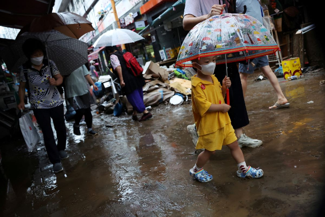 A boy using an umbrella makes his way through a road that was flooded after torrential rain at a traditional market in Seoul, South Korea, August 9, 2022