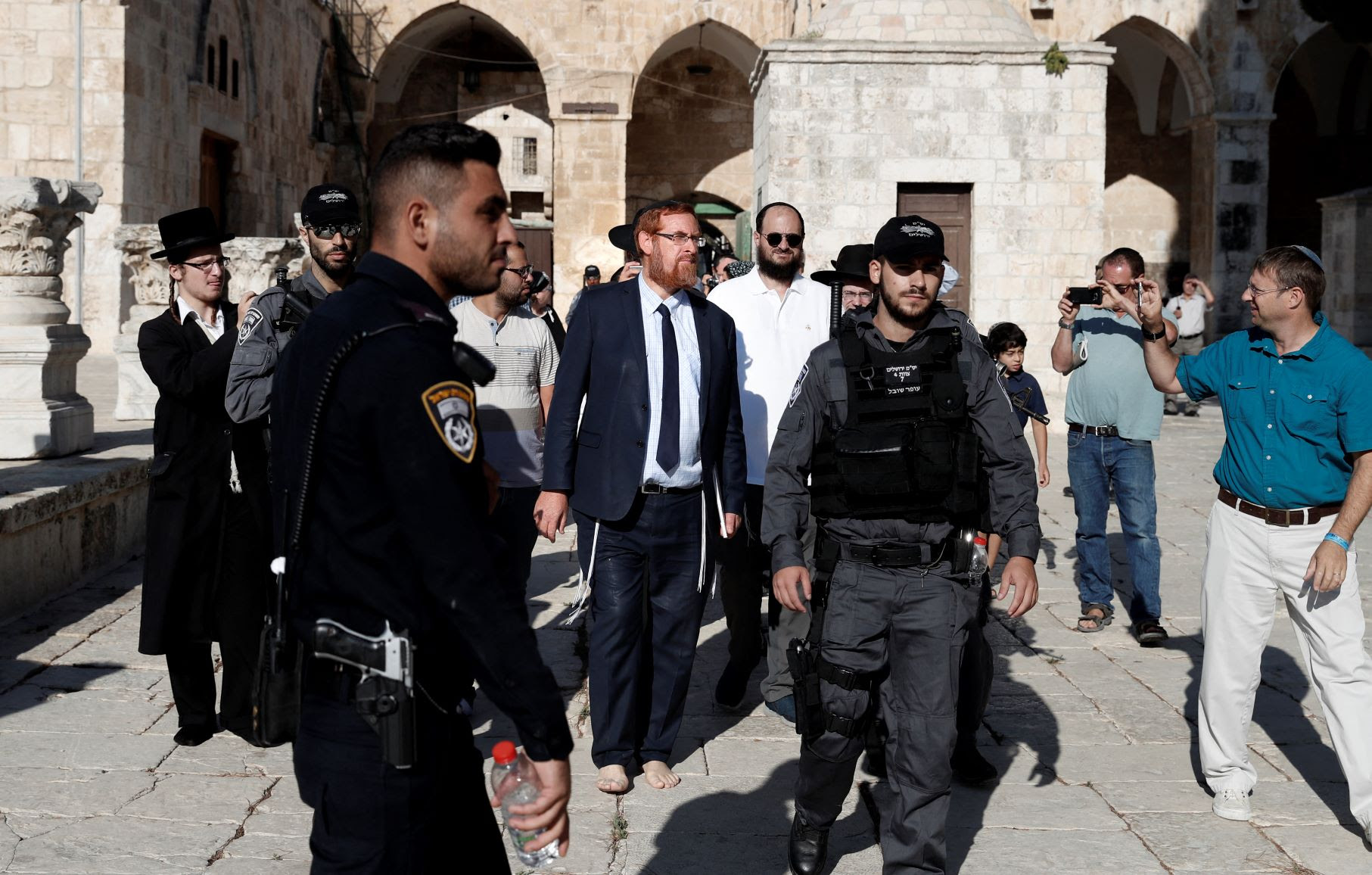 Far right Israeli Rabbi and Israeli parliament member Yehuda Glick (C) walks barefoot, escorted by Israeli police and supporters, inside Al-Aqsa mosque compound (AFP)